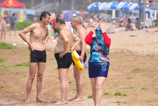 2013年7月3日，山東青島青島高溫來襲，“青島大媽”不懼滸苔，戴著“強(qiáng)盜面具”出現(xiàn)在海水浴場消暑降