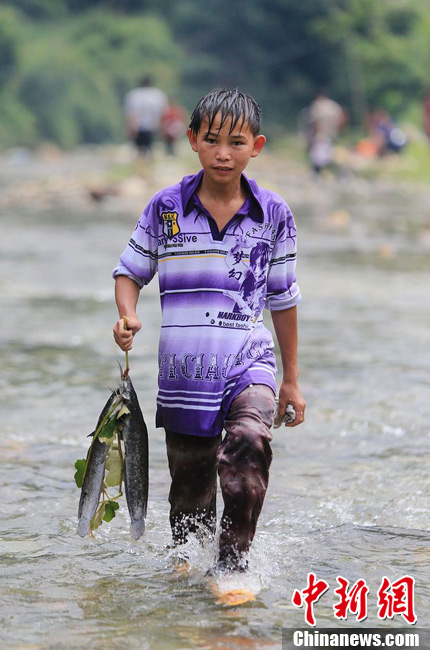 圖為7月9日，一名男孩在鬧魚節(jié)活動中抓到了兩條魚。譚凱興 攝