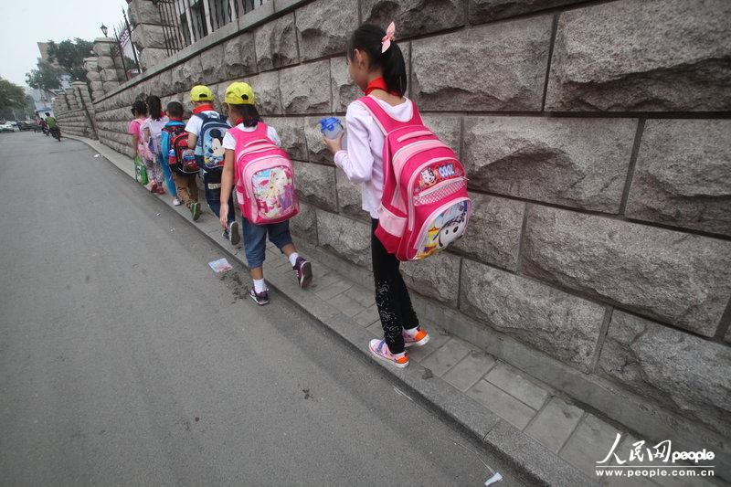 2013年09月11日，濟(jì)南運(yùn)署街上，小學(xué)生走史上“最窄人行道”上學(xué)。