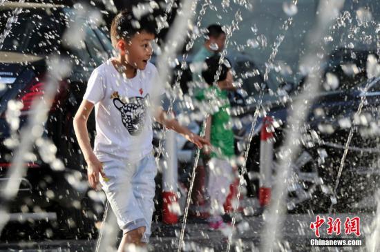 山西太原最高溫36℃,兒童在噴泉周圍戲水消暑。