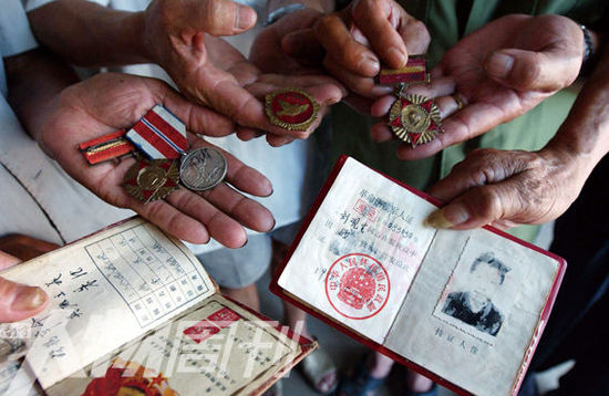 幾位志愿軍老兵展示自己的立功證、傷殘軍人證與勛章