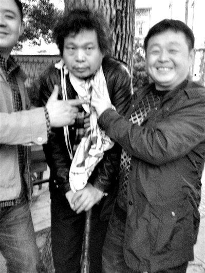 兩名接訪人員與患有癌癥的訪民段新德合影時，面帶笑容擺出勝利的手勢。