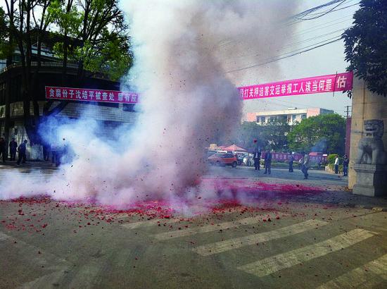 市民在普洱市主干道振興大道的金孔雀交通運(yùn)輸集團(tuán)有限公司門前燃放鞭炮，公司門前掛著“貪腐份子沈培平被查處，罪有應(yīng)得，大快人心?！钡臈l幅