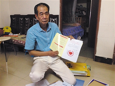 翻出一家網站贈予的“中國好人”證書，區(qū)少坤單膝跪在地上，“你看，我是中國好人啊?！?范春旭 攝