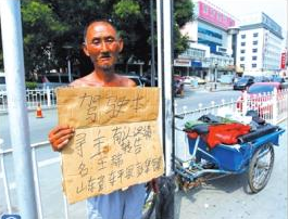 老人舉著牌子在路邊等候失主。京華時報記者譚青攝