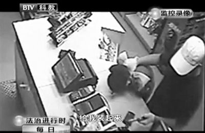 戴帽男子一手掐住加油站營業(yè)員，一手持發(fā)令槍指向另一營業(yè)員，要求“把錢給我裝起來”。