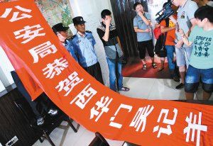面對警方收繳的條幅，老板楊某也不好意思地用手遮擋臉