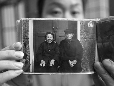 圖為孫女拿出兩位老人上世紀(jì)80年代在家門口的合影給記者看。記者楊濤 攝