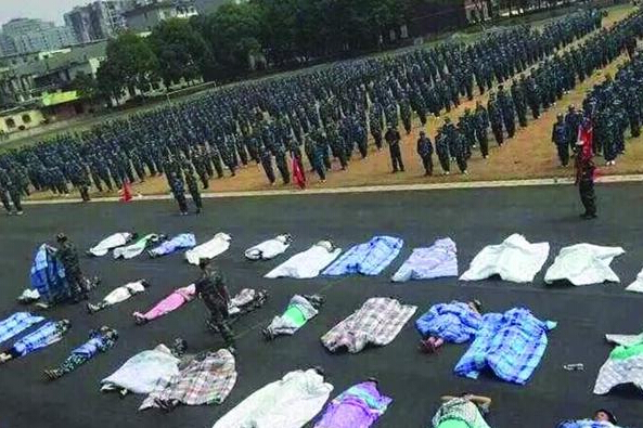 20多名女生躺在瀝青跑道上，身上嚴(yán)嚴(yán)實實地裹著棉被，接受太陽的照曬。