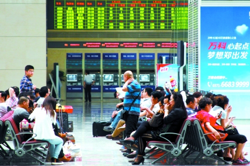 候車大廳溫度很高，一名乘客一手扇風(fēng)、一手擦汗
