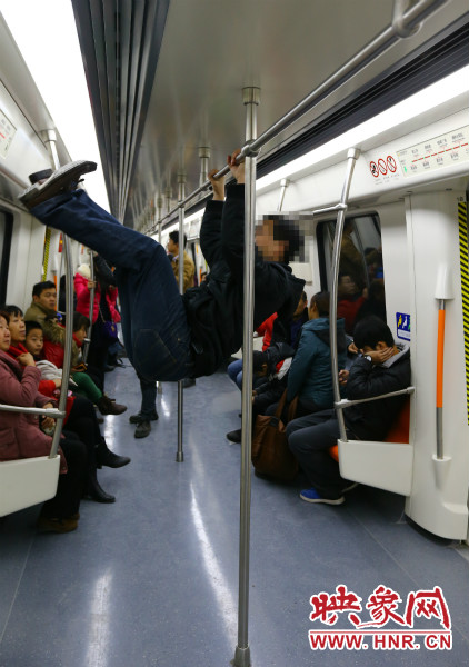 地鐵試乘日，一男子在車廂內(nèi)攀爬扶手自?shī)首詷?lè)