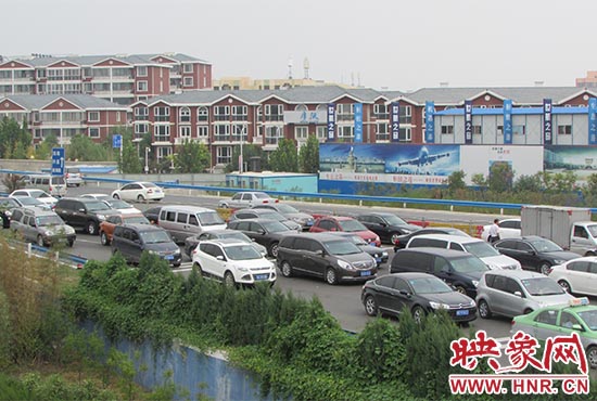 記者看到鄭州機(jī)場(chǎng)收費(fèi)站口車輛排隊(duì)，與此形成鮮明對(duì)比的是，路的對(duì)面（另一半幅）卻車輛較少，通行順暢。