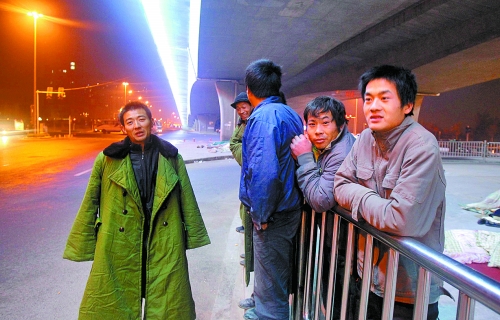 冬夜里，農(nóng)民工在橋下等著干活兒。