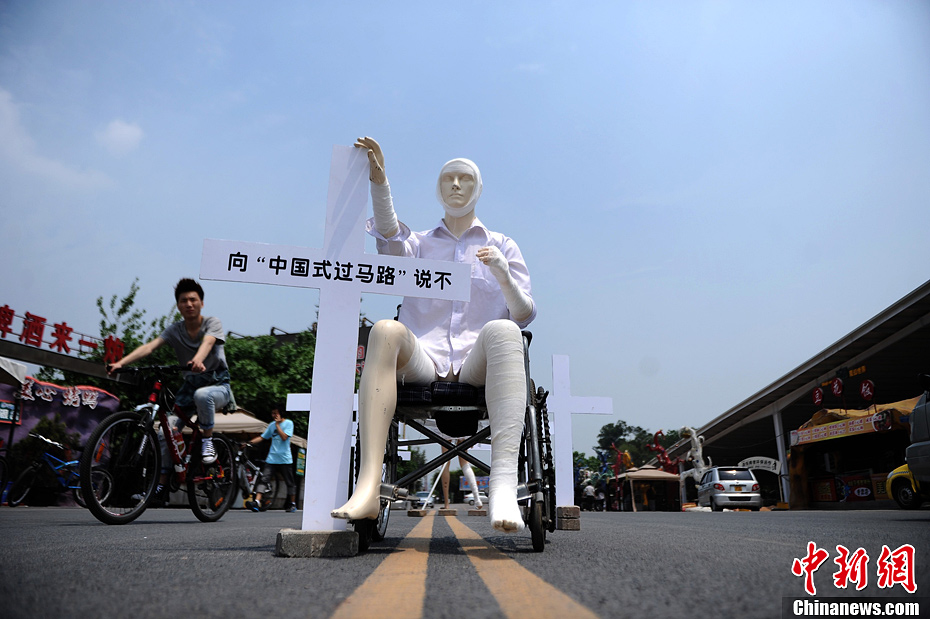 4月16日，重慶市洋人街上擺放著兩個受了傷的塑料人像“模特”，旁邊十字架上寫著向“中國式過馬路”說不