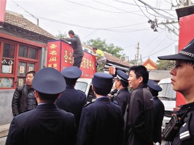 昨日下午,東城區(qū)工商、城管、公安等部門,對雍和宮附近的預測中心進行清理整頓,站在車頂的兩名工人正拆除一家“預測中心”的招牌。因雍和宮、白云觀等文化景點外聚集大量算命先生,被媒體稱為“算命一條街”。本版攝影/新京報記者 李寧 攝