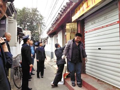 執(zhí)法人員拆除胡同里一家店面未經審批的招牌。