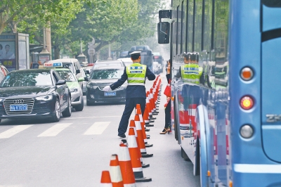 省人民醫(yī)院南門的路中間擺放反光錐，交警示意由西向東車輛從前方繞行。