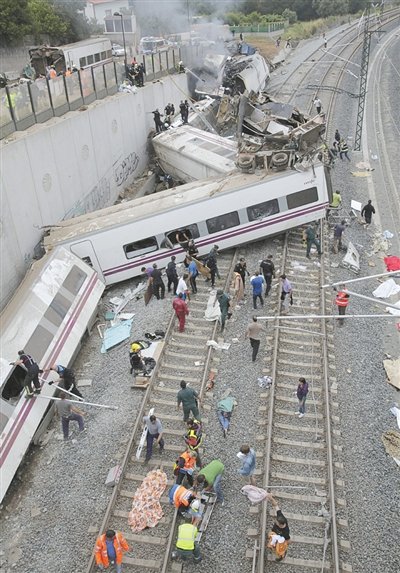 24日，救援人員在西班牙列車脫軌現(xiàn)場。一節(jié)車廂被強大的慣性拋上鐵道邊的高臺。
