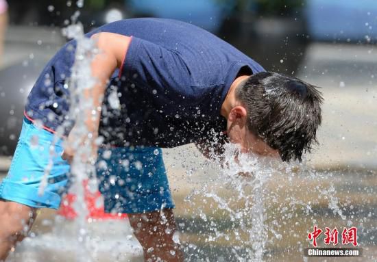 5月29日，一名小孩將頭伸向北京街頭的噴泉以降溫祛暑。