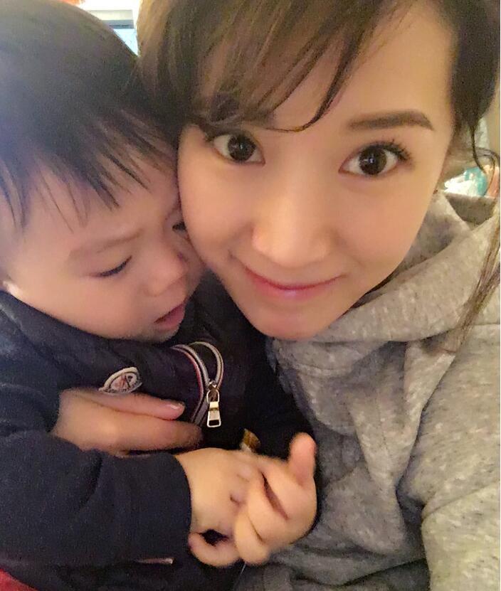 照片中李念狂吻兒子，小寶貝自顧自地玩著。