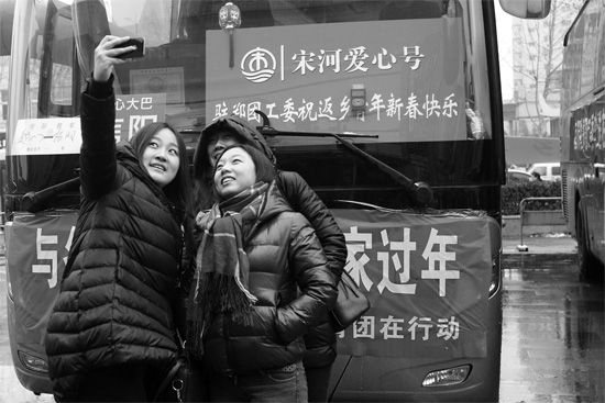 昨天上午8時，鄭州正道中環(huán)百貨廣場，準備回家的老鄉(xiāng)在愛心大巴車前合影留念