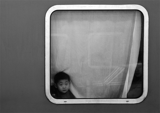 一個孩子把頭伸向窗外，他想再看送別的親人一眼