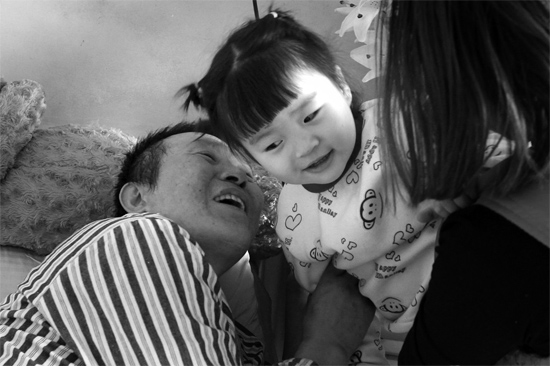 病床前李剛父女倆說(shuō)著“悄悄話”，幸福的氣氛洋溢在病房中
