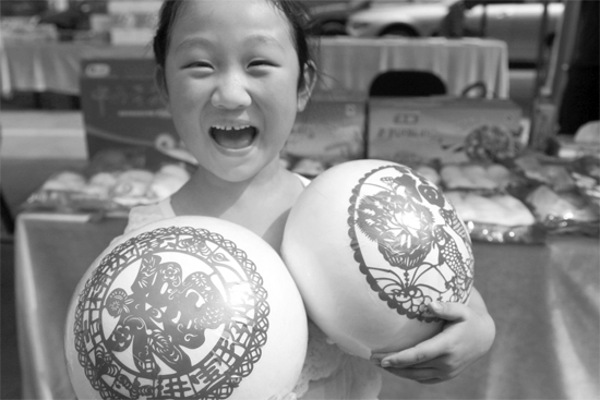 在2013河南食品安全宣傳周活動(dòng)現(xiàn)場，一個(gè)小女孩抱著參展的特色大饅頭樂開了花