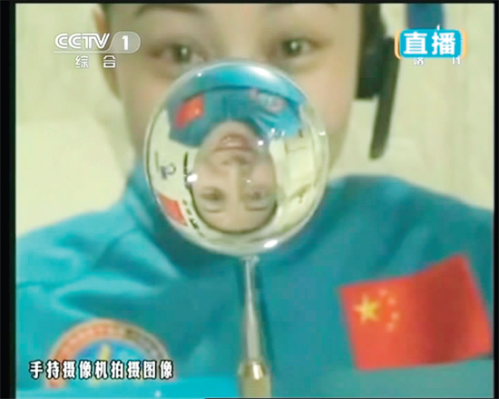 王亞平的倒影出現(xiàn)在水球中。新華社發(fā)（視頻截圖）