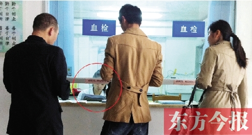 昨日，鄭州市二七區(qū)疾控中心辦證大廳，血檢窗口內(nèi)一名女工作人員，邊接受辦證者咨詢邊看報(bào)紙