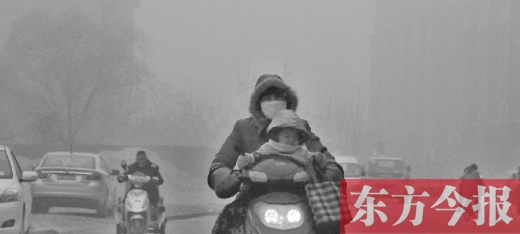 12月8日，鄭州市未來路上，一位市民帶著孩子在霧中騎行
