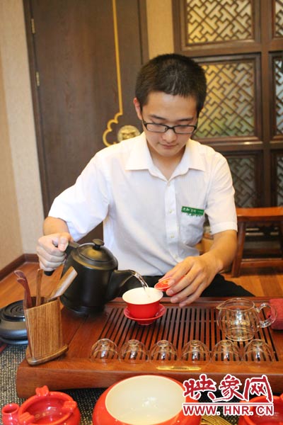 1、水壺里的水煮沸，李克勤把茶葉放進茶荷里，準備溫杯沖茶