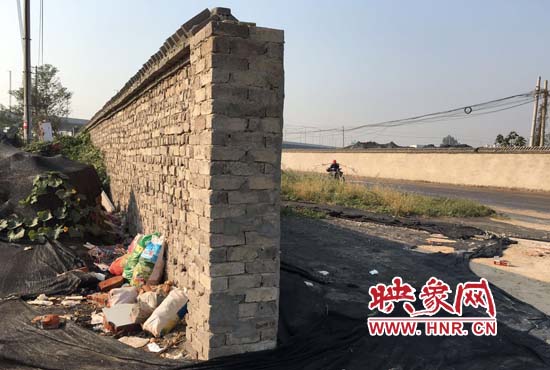 一墻之隔，一邊是道路，一邊是垃圾和荒草，市民質(zhì)疑其為遮羞墻。