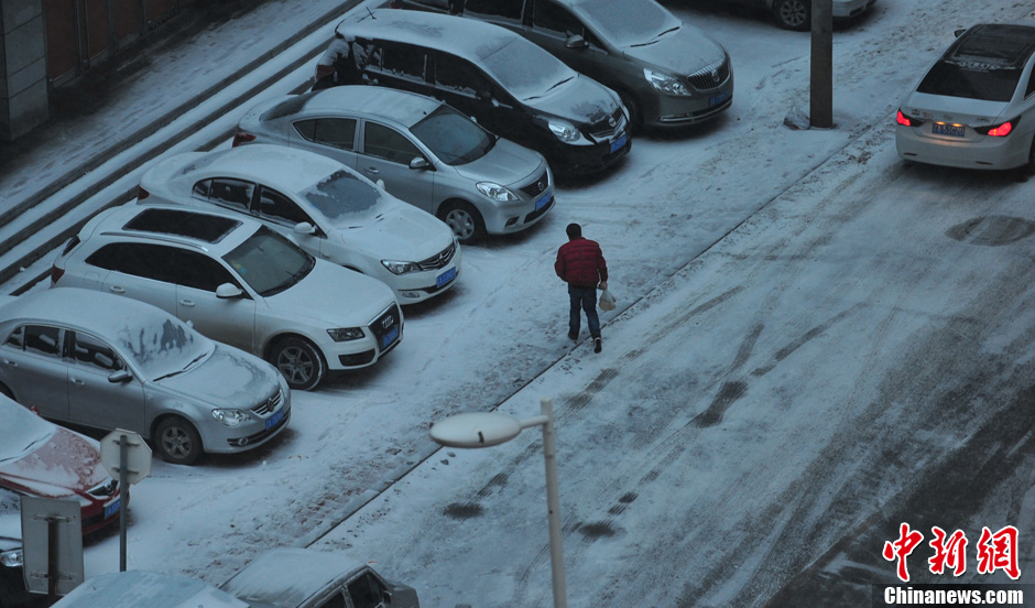 11月18日，行人在沈陽街頭的積雪中穿行。