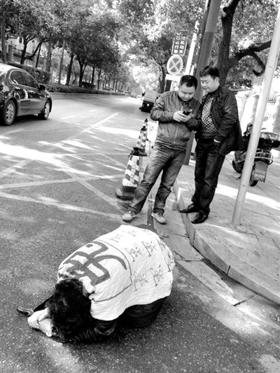 兩名接訪人員與患有癌癥的訪民段新德合影時(shí)，在拍照時(shí)查看手機(jī)。