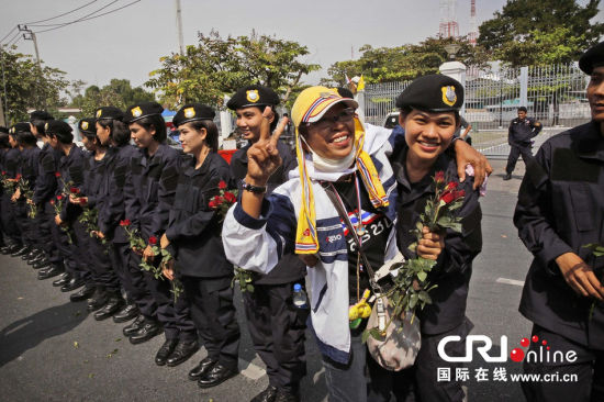 2013年12月03日,曼谷總理府與曼谷警署允許反政府示威民眾進入,雙方進入暫時“停戰(zhàn)”狀態(tài)迎接泰王生日。曼谷警察總署,女警們手持鮮花送給反政府示威民眾。圖片來源:Manish Swarup/東方IC