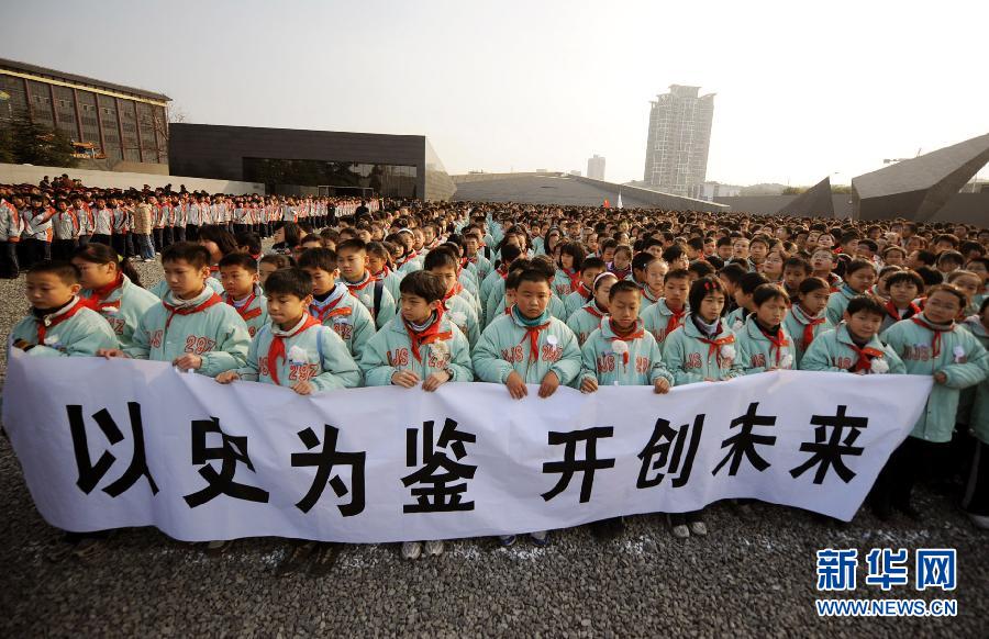 ，南京市小學(xué)生代表手持“以史為鑒 開創(chuàng)未來”的橫幅在南京大屠殺遇難同胞紀(jì)念館集會(huì)廣場(chǎng)參加悼念儀式。　