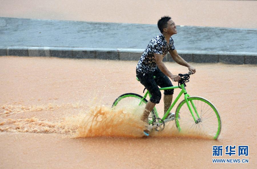 5月11日，一名行人在深圳街頭冒雨騎行。