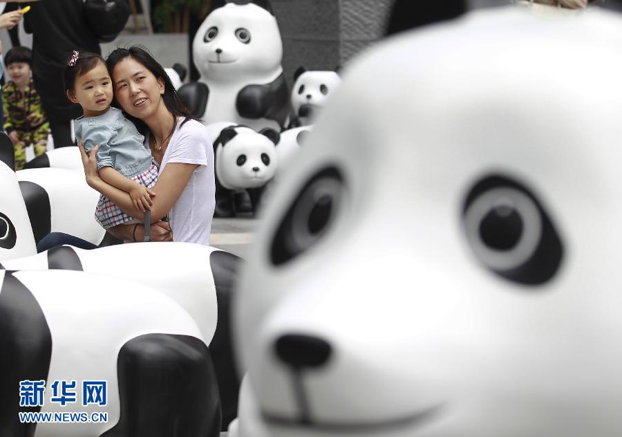 6月2日，一位家長(zhǎng)帶著孩子在上海街頭和大熊貓模型合影。