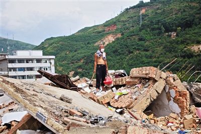 8月9日,龍頭山鎮(zhèn),一位老者在自家房屋廢墟上尋找家當(dāng)。