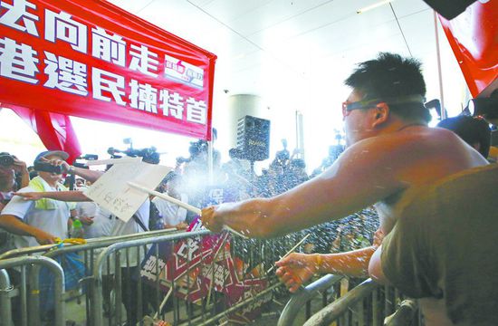 17日，在香港立法會(huì)外，一名反對(duì)政改的男子向支持派人群投擲標(biāo)牌。