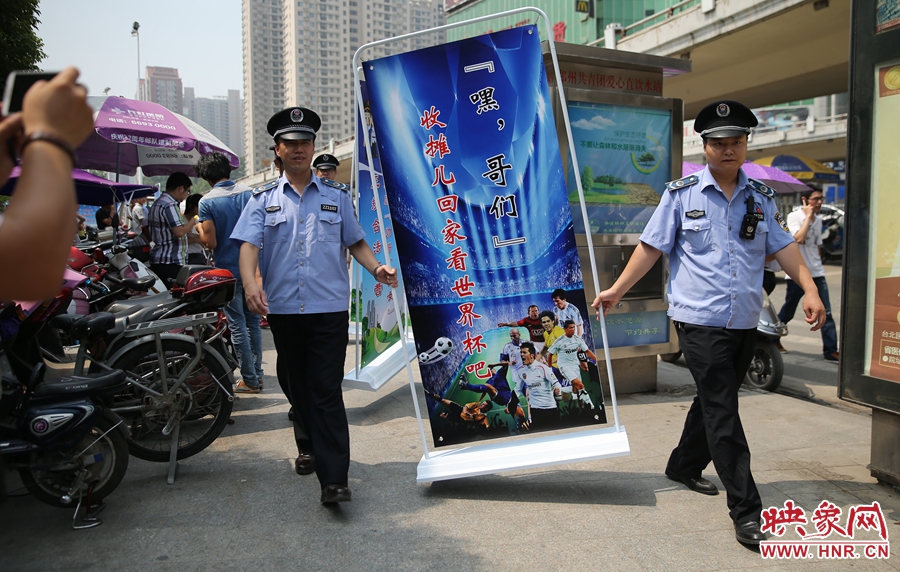 7月2日上午，鄭州市紫荊山地鐵站出入口，執(zhí)法人員抬著寫有勸導(dǎo)語的宣傳板，前往占道經(jīng)營攤位“圍觀執(zhí)法”