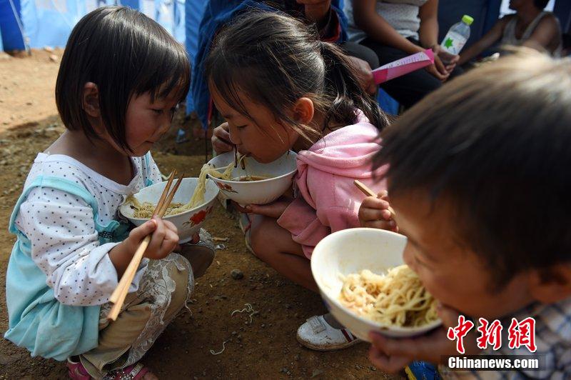 2014年8月6日，云南魯?shù)辇堫^山災(zāi)區(qū)，兒童在帳篷外吃飯。
