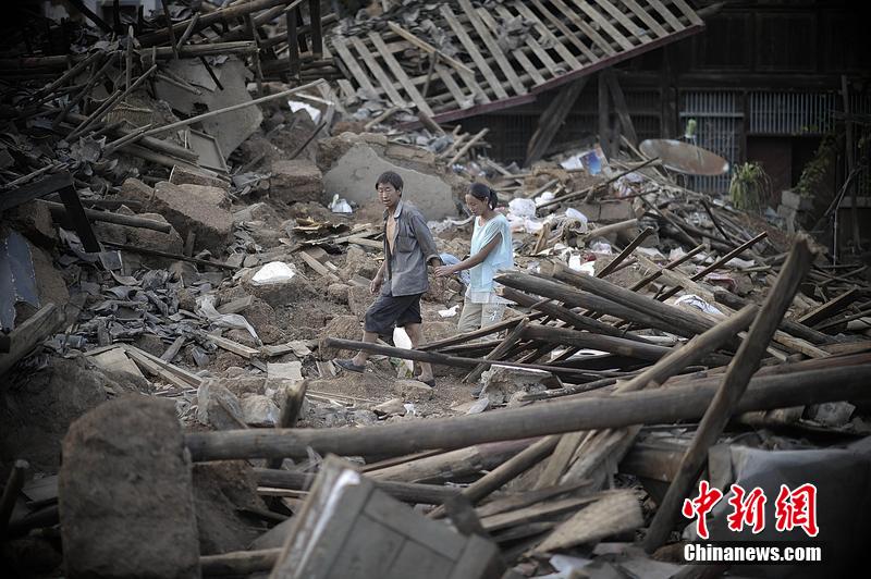 2014年8月5日，云南昭通龍頭山鎮(zhèn)老街，一對(duì)夫妻從居住房屋的廢墟中走過(guò)。