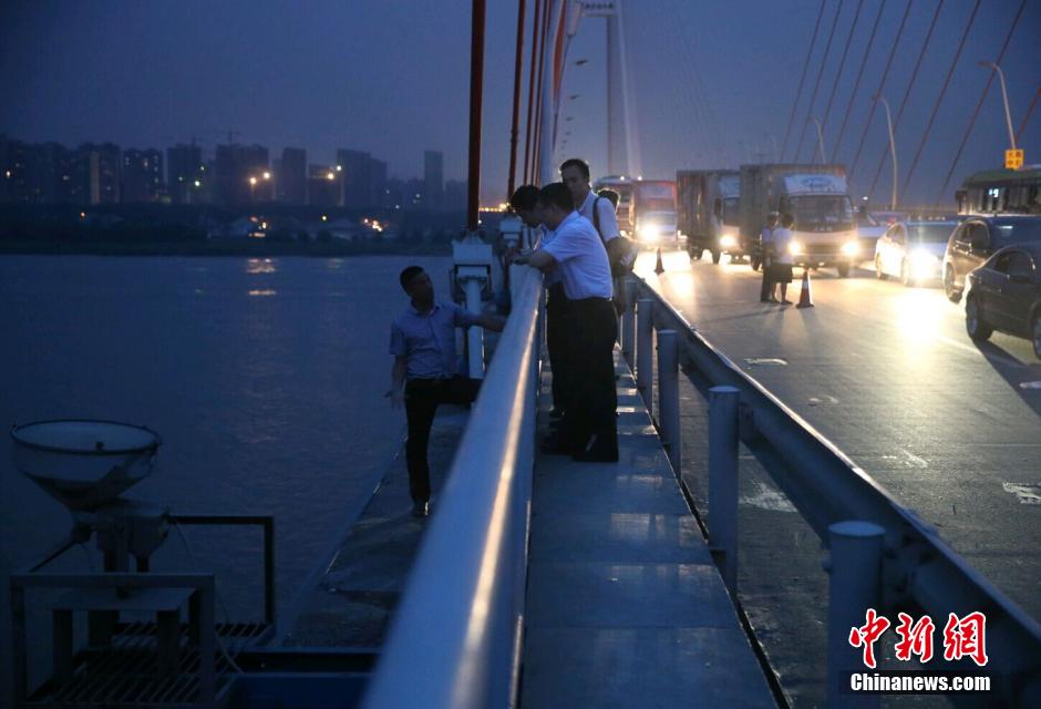 圖為武漢警方談判專(zhuān)家正在與翻爬至大橋外側(cè)護(hù)欄的劫持者談判。