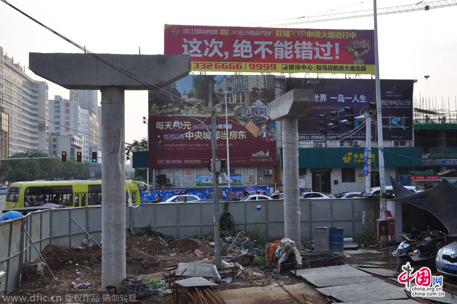 過街天橋一側(cè)的橋樁早已打好,可是對(duì)面的郵政銀行網(wǎng)點(diǎn)依舊在照常營業(yè)。
