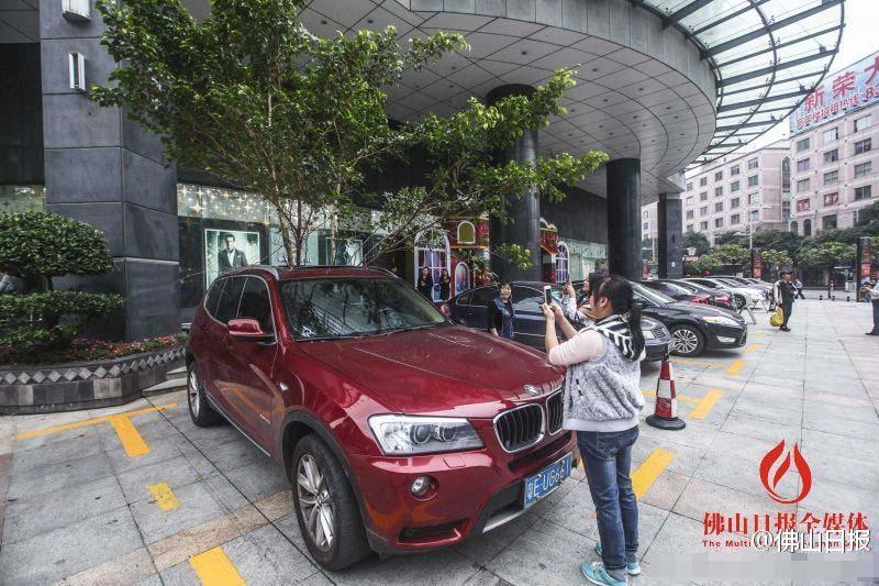 一輛停在停車位上的寶馬轎車，被墜落的樹枝砸中，樹枝徑直插入車內(nèi)，現(xiàn)場(chǎng)引發(fā)不少市民圍觀拍照。