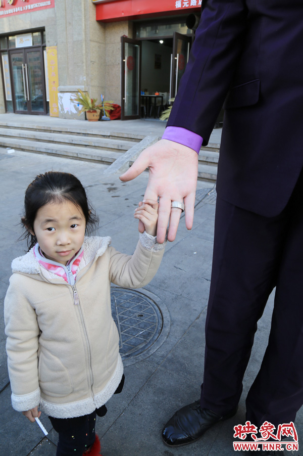 巨人“張歡”牽著一名漂亮的小女孩，兩人的手大小對(duì)比非常明顯。
