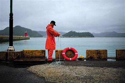 7月6日，韓國珍島，一名海岸警察在港口系救生圈。4月，客輪在珍島近海發(fā)生沉船事故后，仍有11人下落不明。