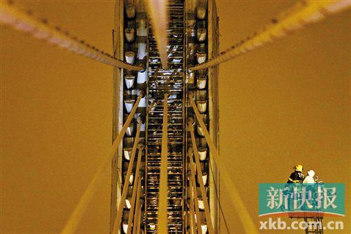 截至今日零時(shí)，男子仍未有下橋舉動(dòng)。圖為公安和消防人員乘消防云梯在高空上和男子交談。